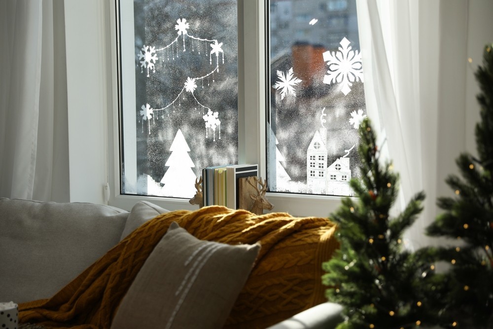 A living room with a christmas tree in front of a window.