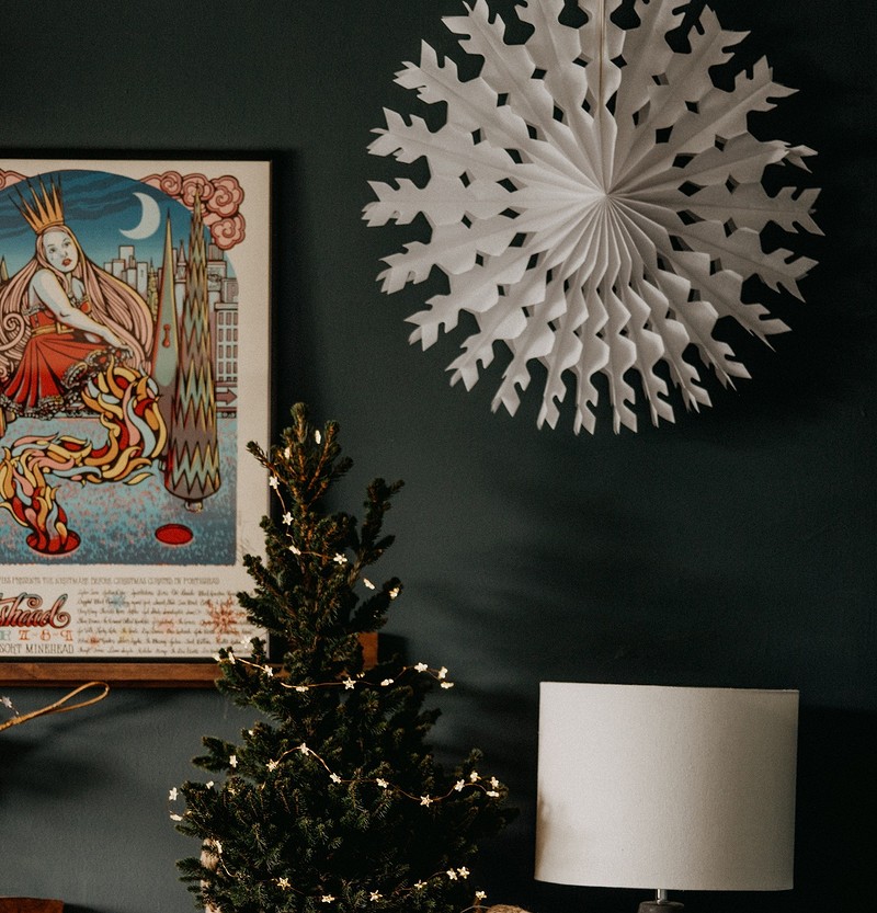 A living room with a christmas tree and a paper snowflake.