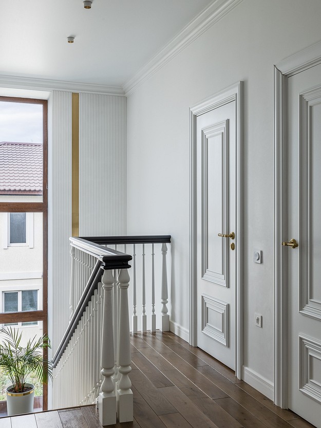 A hallway with white doors and a wooden railing.