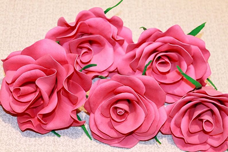 A group of pink paper roses on a table.