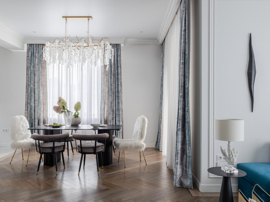 A dining room with blue chairs and a chandelier.