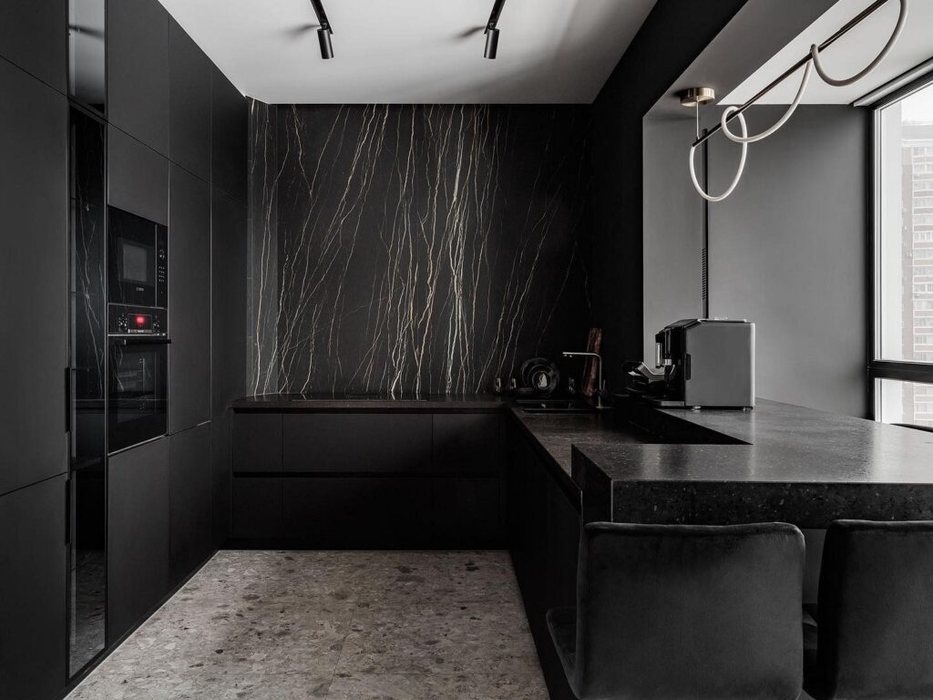 A black kitchen with marble counter tops.