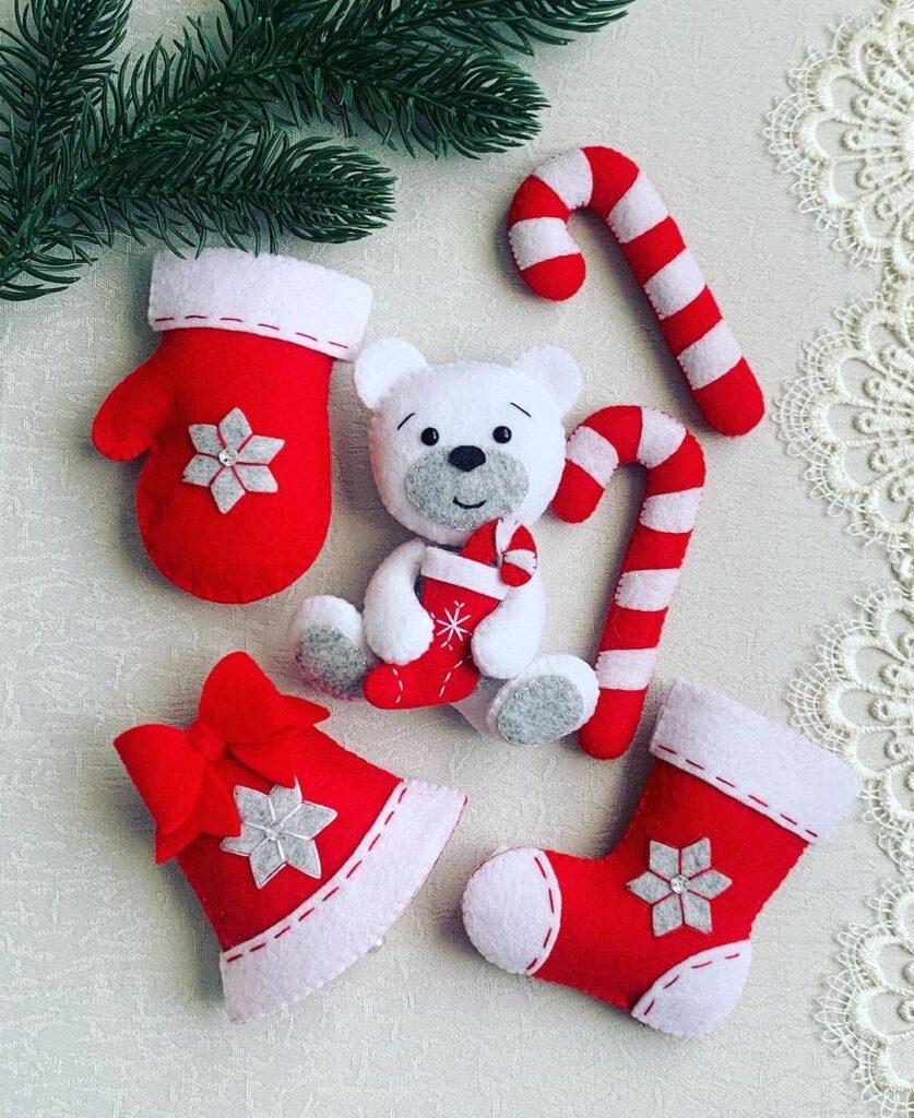 A set of christmas ornaments with a teddy bear, a bell and a candy cane.