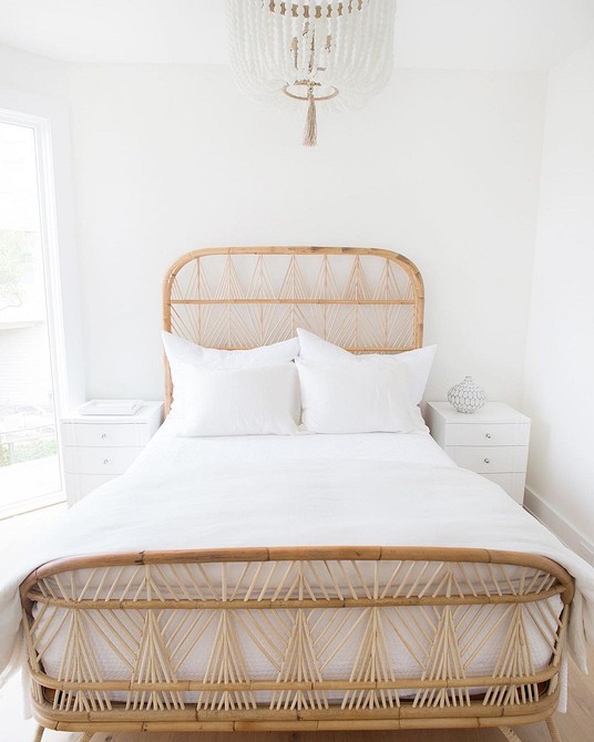 A white bedroom with a rattan bed.