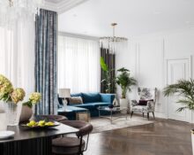 A living room with blue furniture and a chandelier.