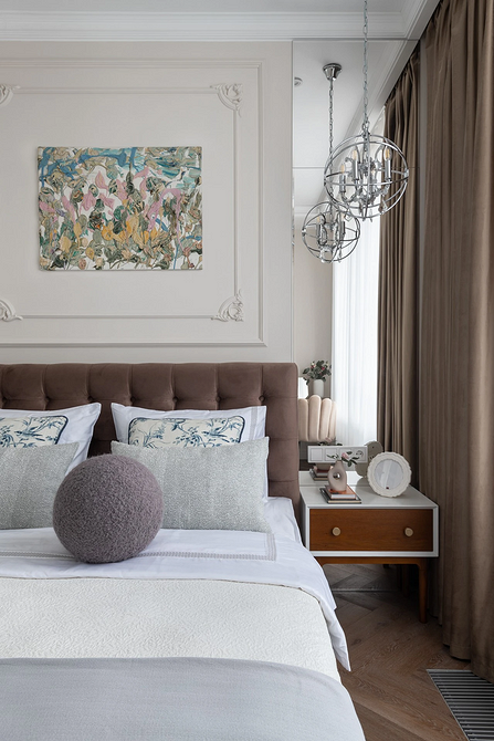 A bed in a bedroom with a painting on the wall.