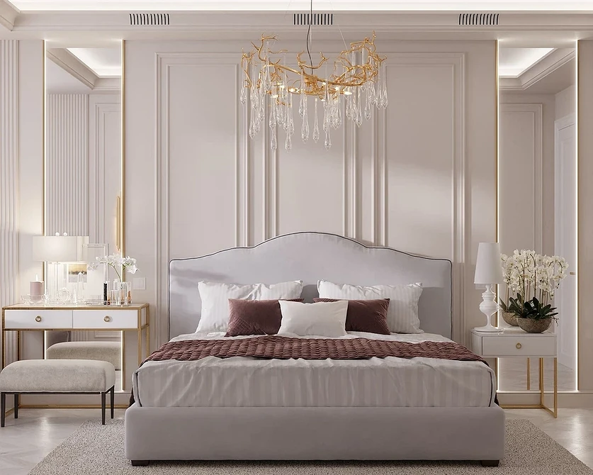 A white bedroom with gold accents and a chandelier.