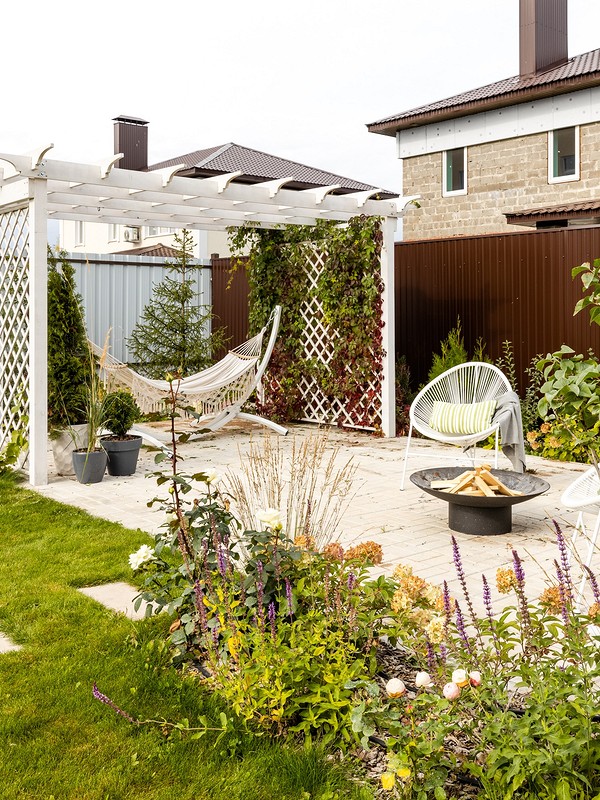 A backyard with a hammock and a fire pit.