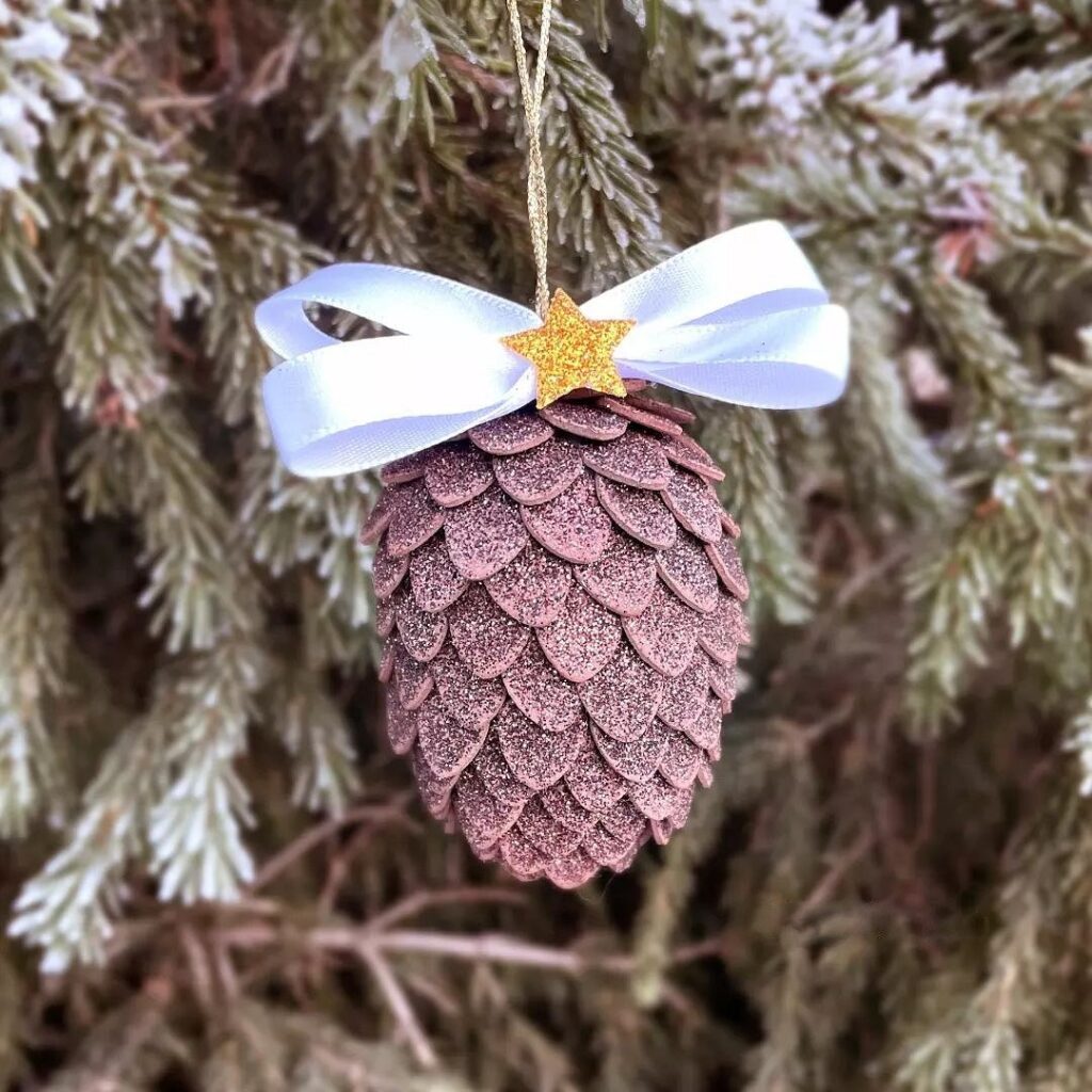 A pine cone ornament hanging on a tree.