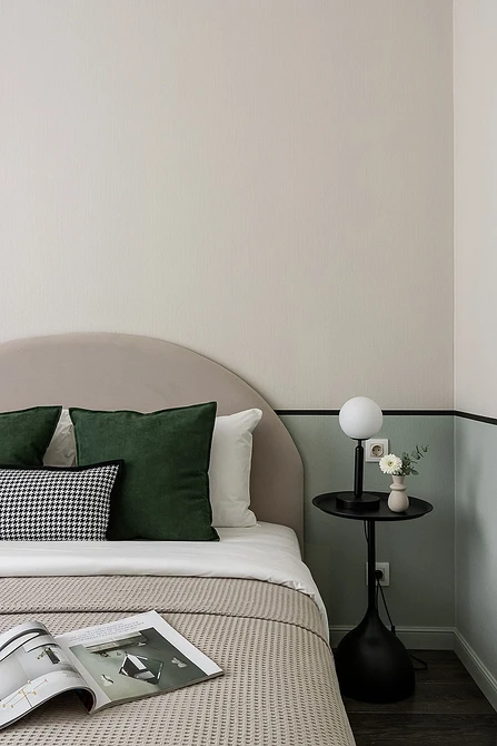 A white and green bedroom with a magazine on the bed.