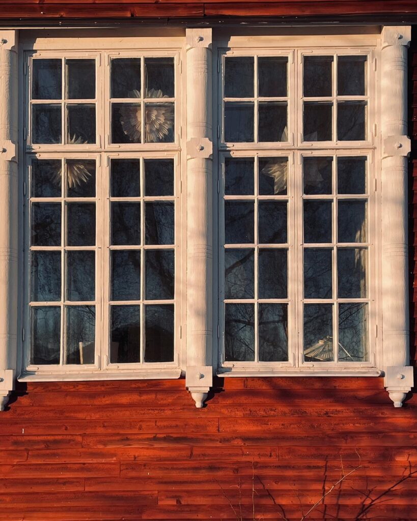 A white window with a wooden frame on a red house.