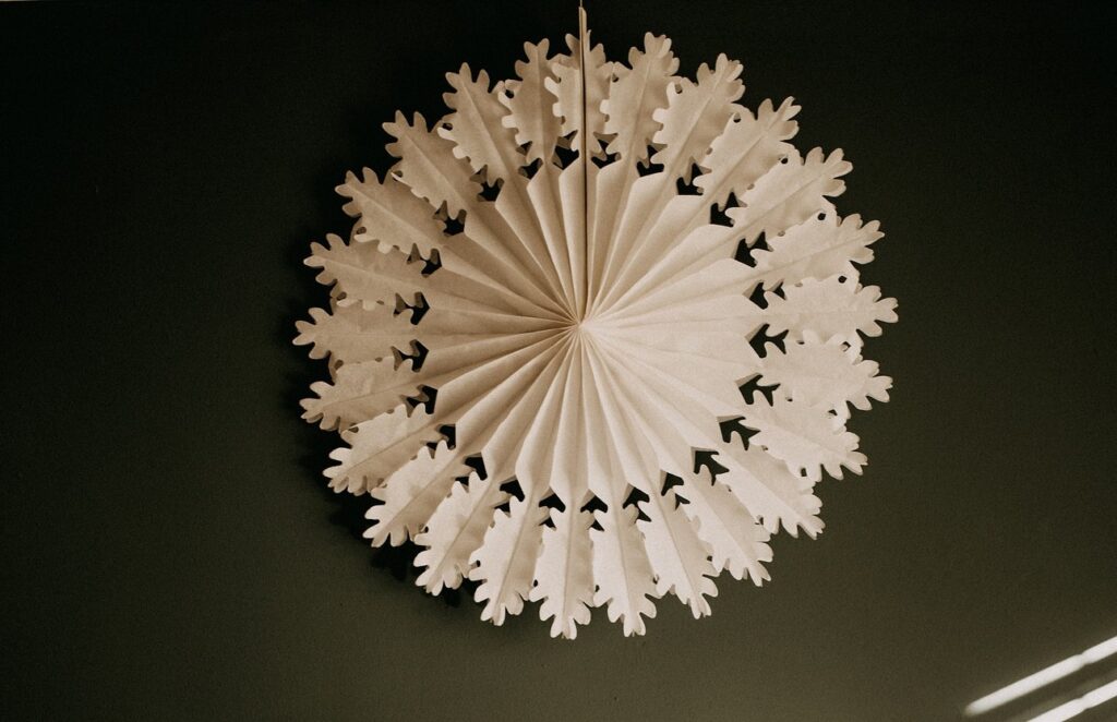 A white paper fan hanging on a wall.