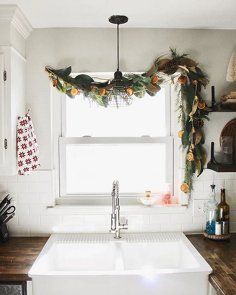 A kitchen sink with a garland hanging over it.