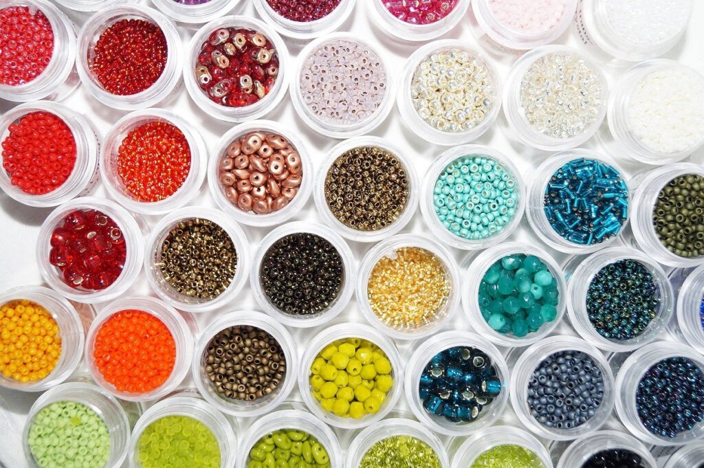 A variety of different colored beads are arranged in a white bowl.