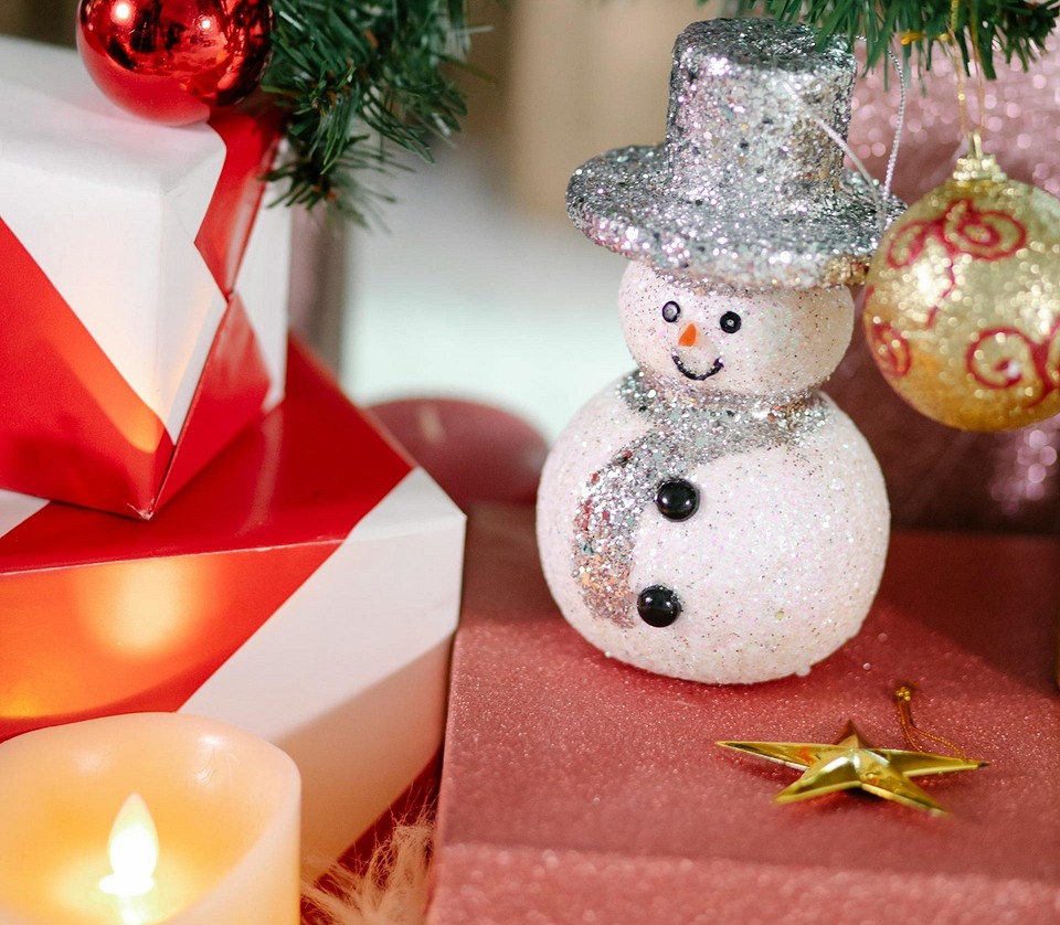 A snowman sits on top of a christmas tree.