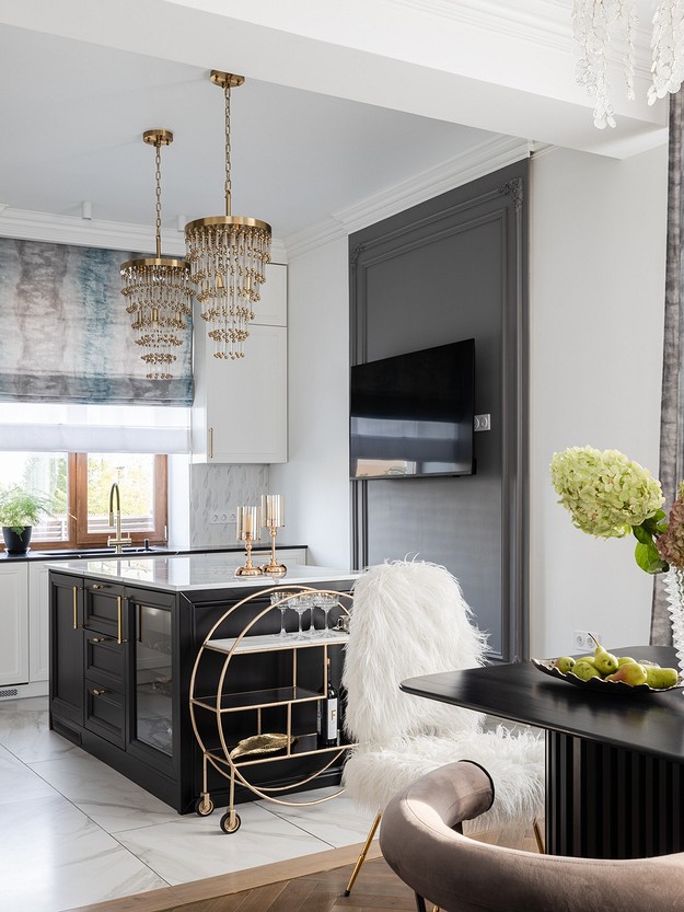 A black and gold kitchen with a chandelier.