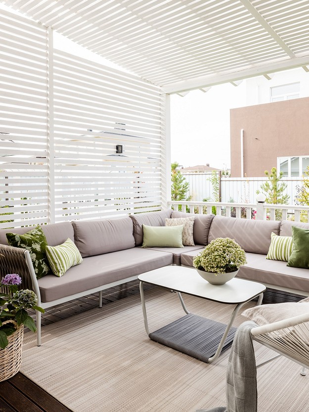 A white patio with a grey couch and a coffee table.