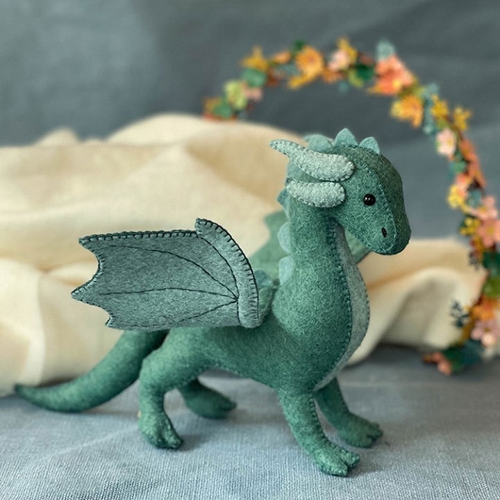 A green felt dragon with a flower crown.