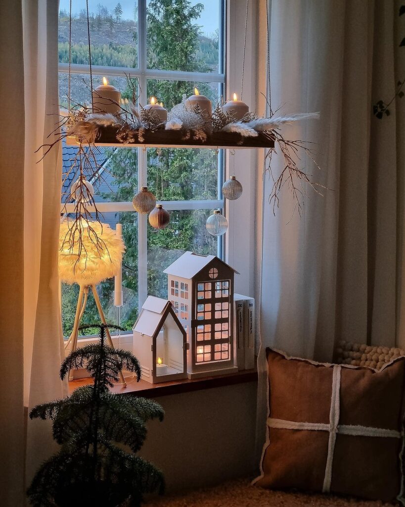 A window sill with candles and a christmas tree.