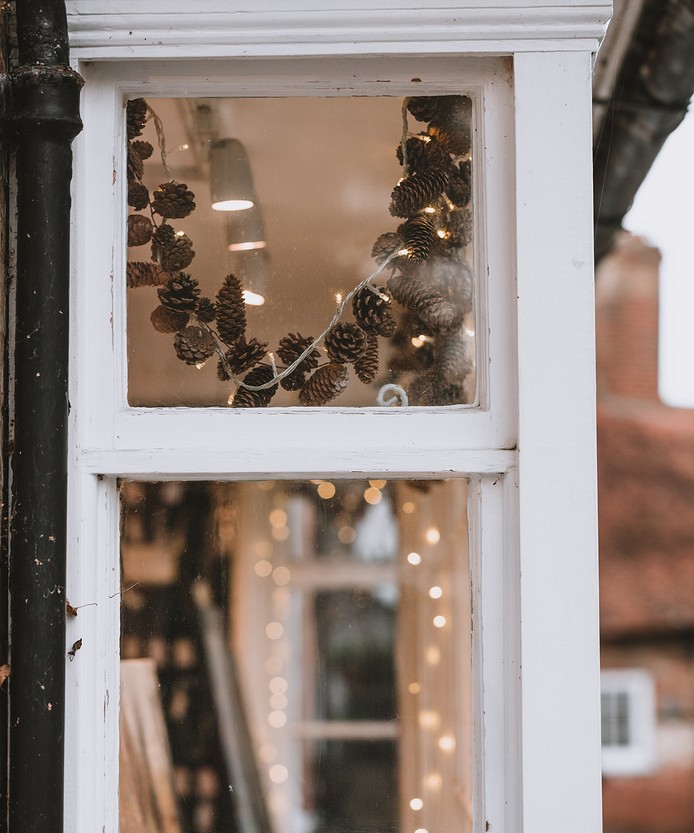 A window in a shop with lights and pine cones.