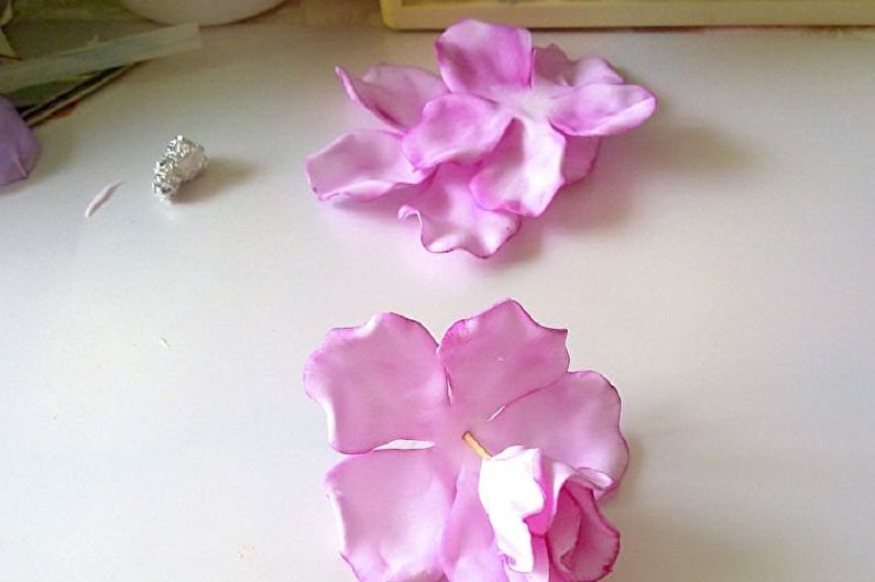 Two pink flowers on a table.