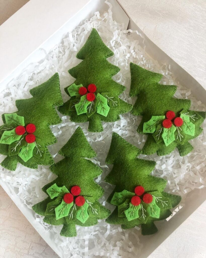 Four green felt christmas trees in a box.