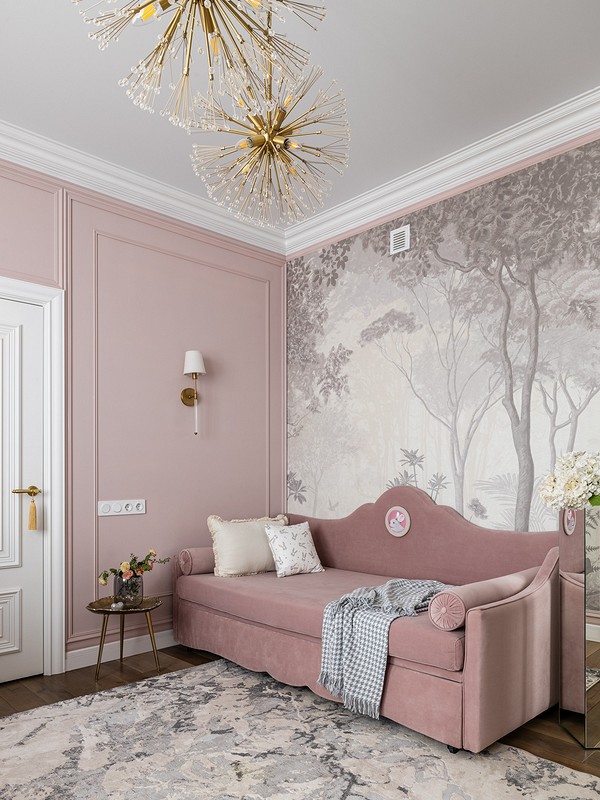 A pink living room with a chandelier and a pink couch.