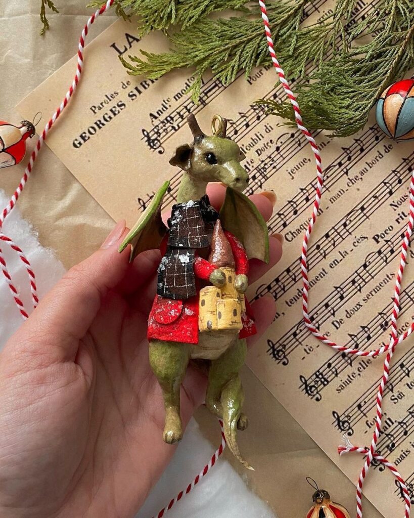 A person holding a christmas ornament with a dragon on it.