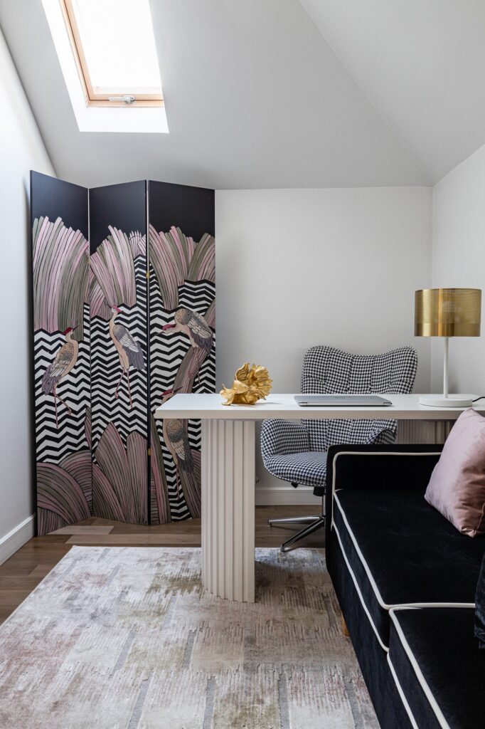 A room with a desk and a black couch.