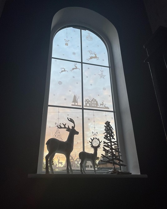 A window with a christmas tree and reindeer in it.