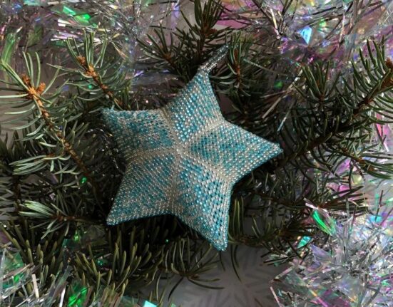 A blue star shaped ornament on a christmas tree.