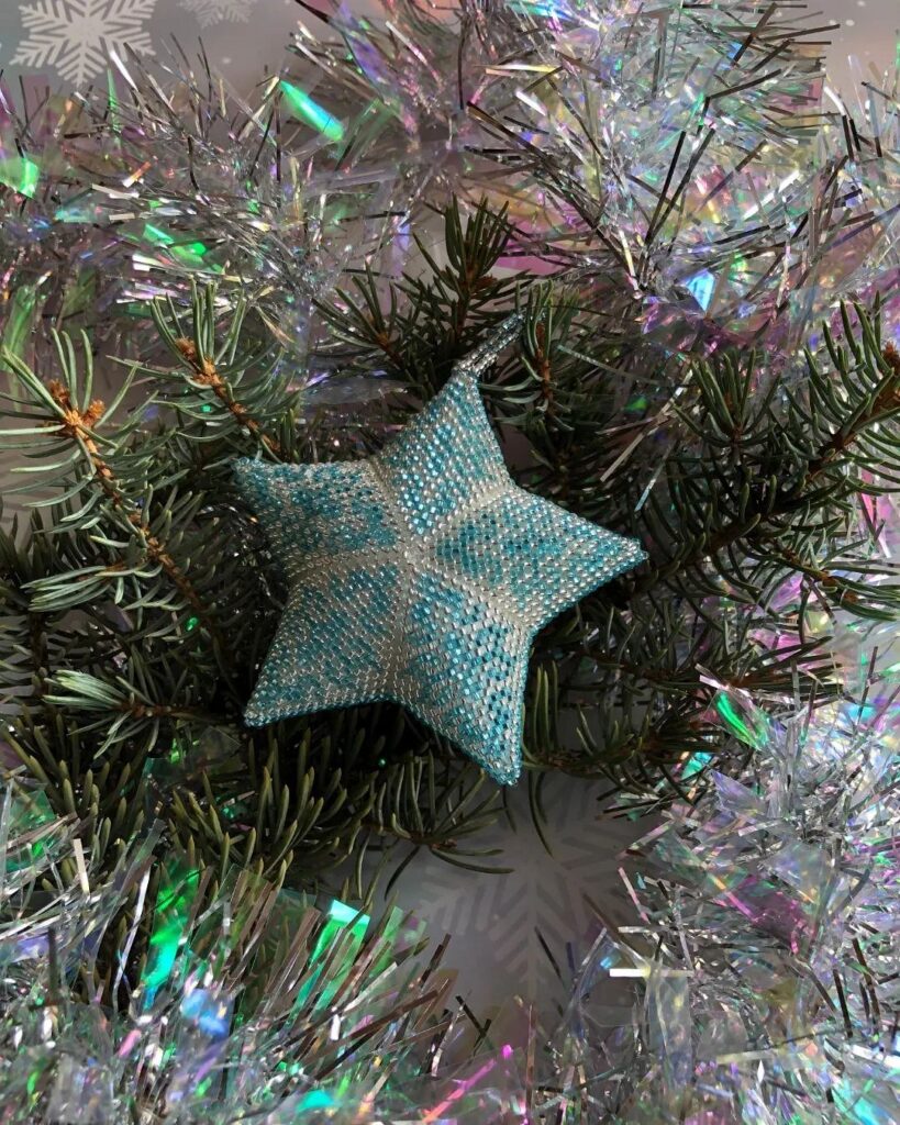 A blue star shaped ornament on a christmas tree.