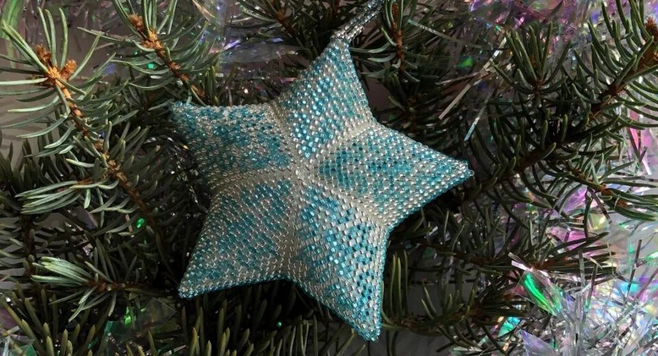 A blue star shaped ornament on a christmas tree.