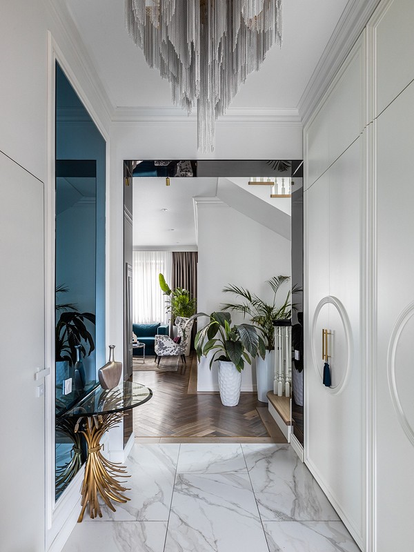 A hallway with a marble floor and a chandelier.