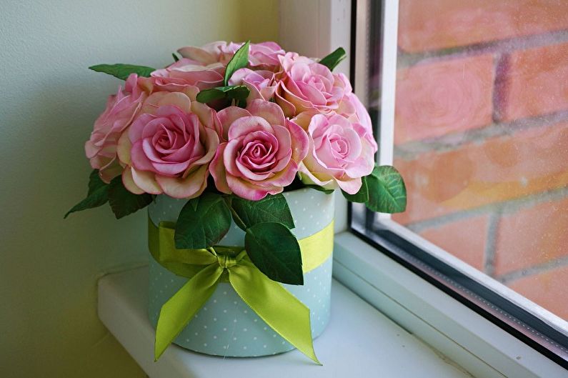 Pink roses in a vase on a window sill.