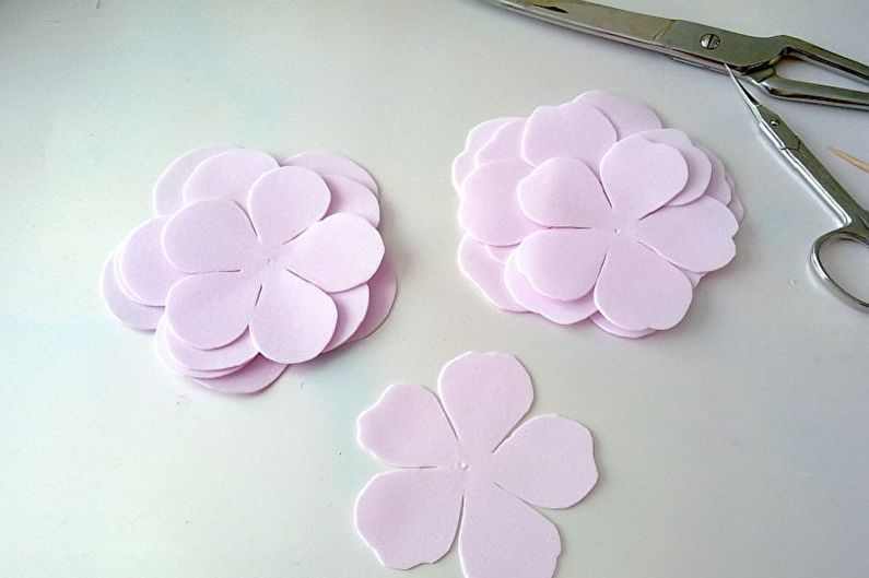 Pink paper flowers and scissors on a table.