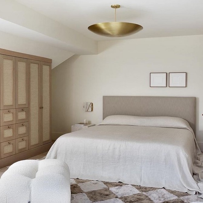 A bedroom with a white bed and a beige rug.