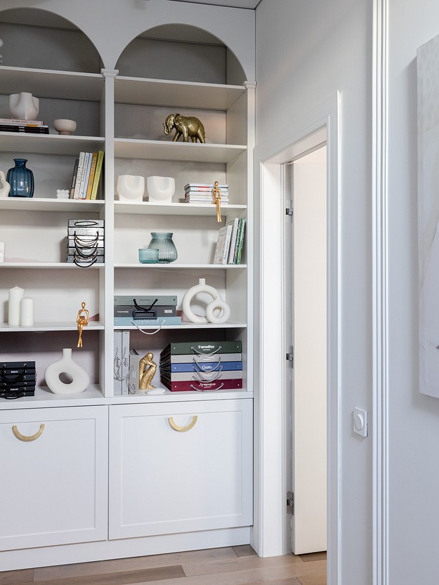 A room with white shelves and a painting on the wall.