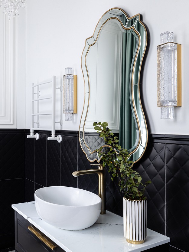 A black and gold bathroom with a mirror and sink.