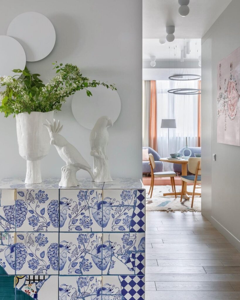 A blue and white tiled entryway with a plant and a vase.