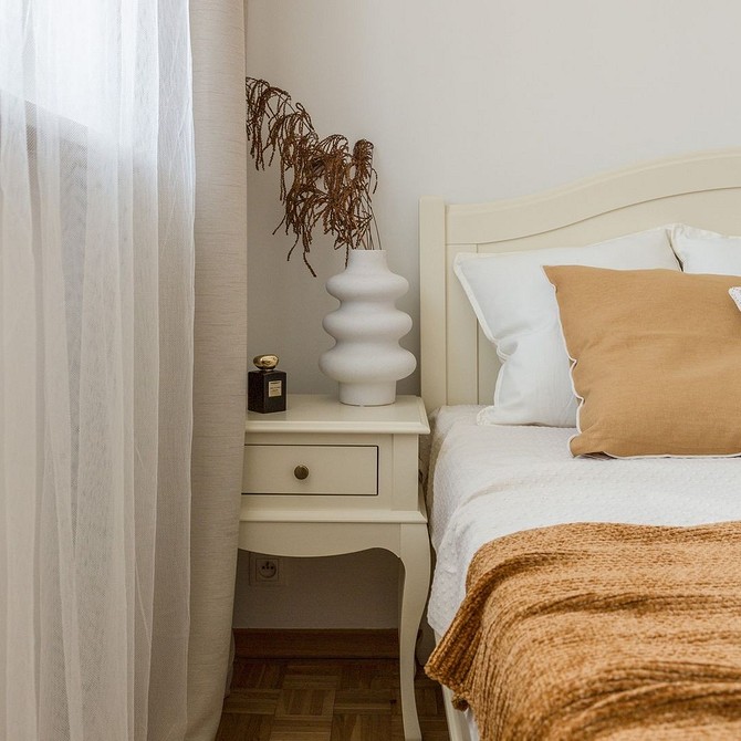 A bedroom with a white bed and tan pillows.