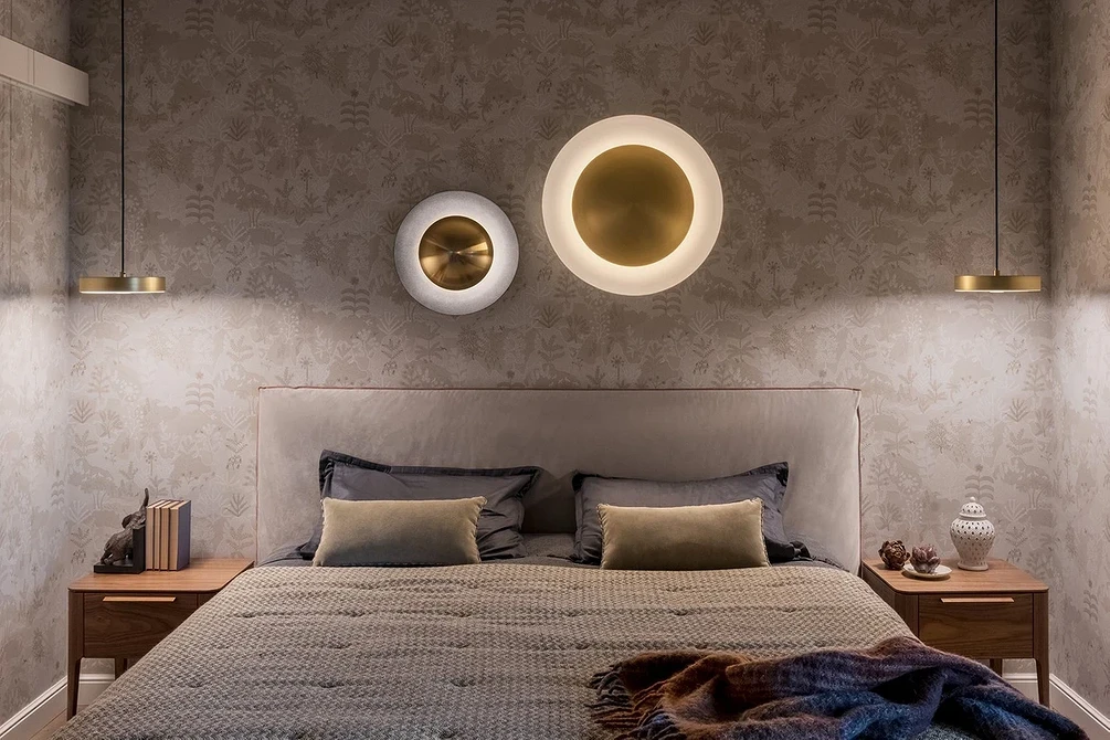 A bed in a bedroom with two round lights above it.