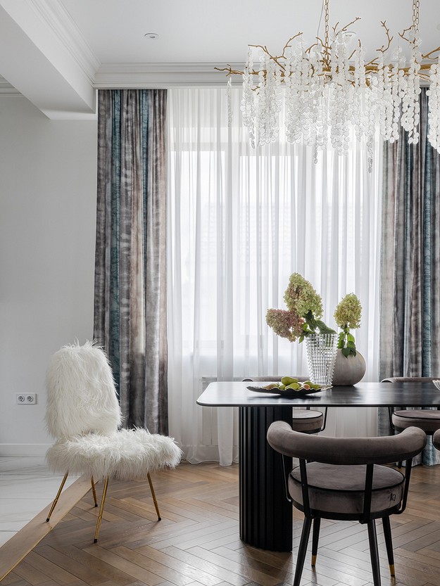 A dining room with a chandelier and white chairs.