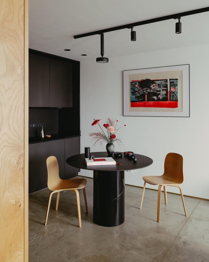 A dining room with a black table and chairs.