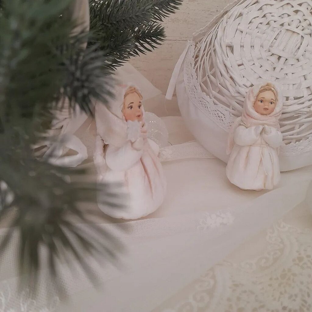 Two figurines are sitting on a table next to a christmas tree.