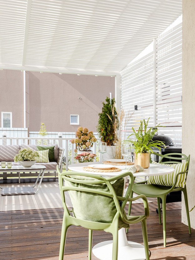 An outdoor dining area with green chairs and a table.