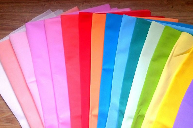 A bunch of different colored paper laying on a wooden floor.