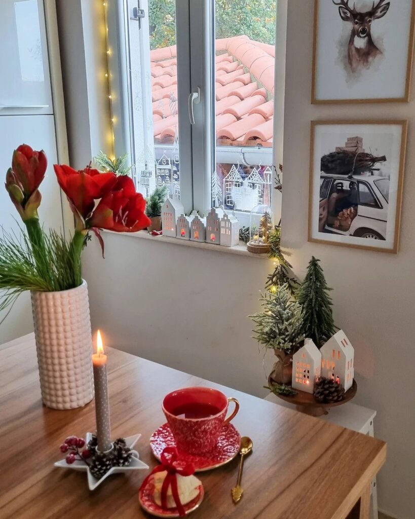 A christmas table setting with a cup of coffee and a red candle.