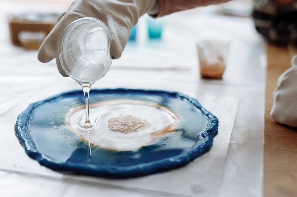 A person pouring a liquid onto a blue plate.