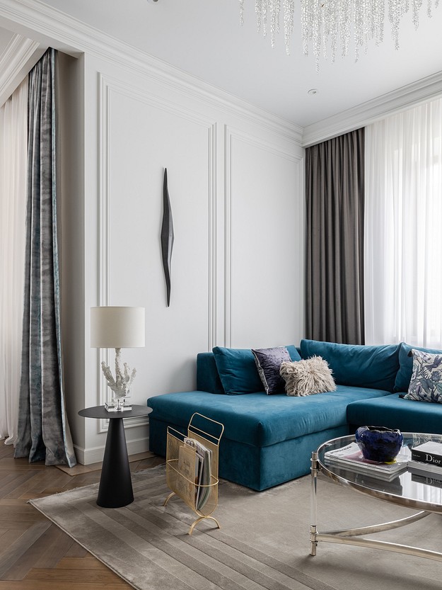 A living room with a blue couch and a chandelier.